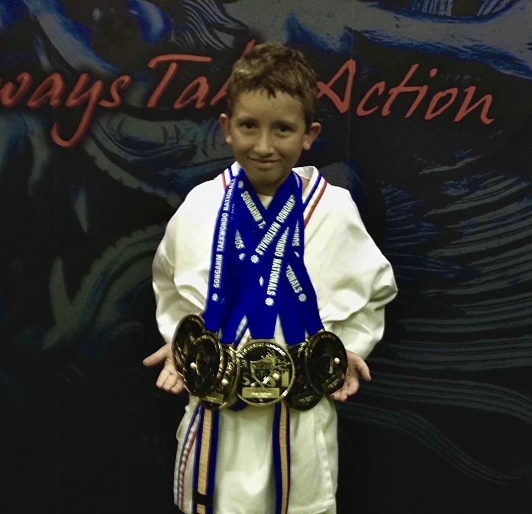 A younger Chase Patterson holding multiple martial arts medals.